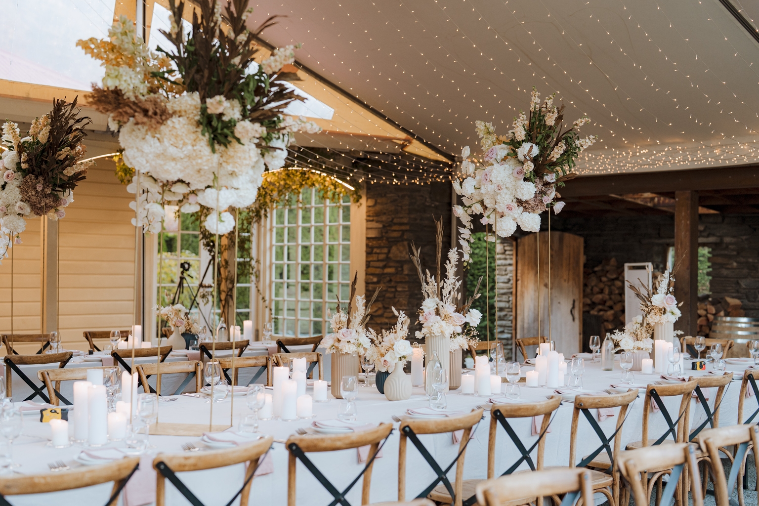 Long dining table set for a private restaurant celebration, with candles, florals, and fairy lights